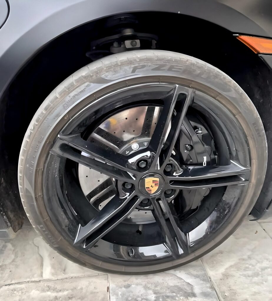 Porsche wheel coated with dirt, brake dust, and grime before detailing