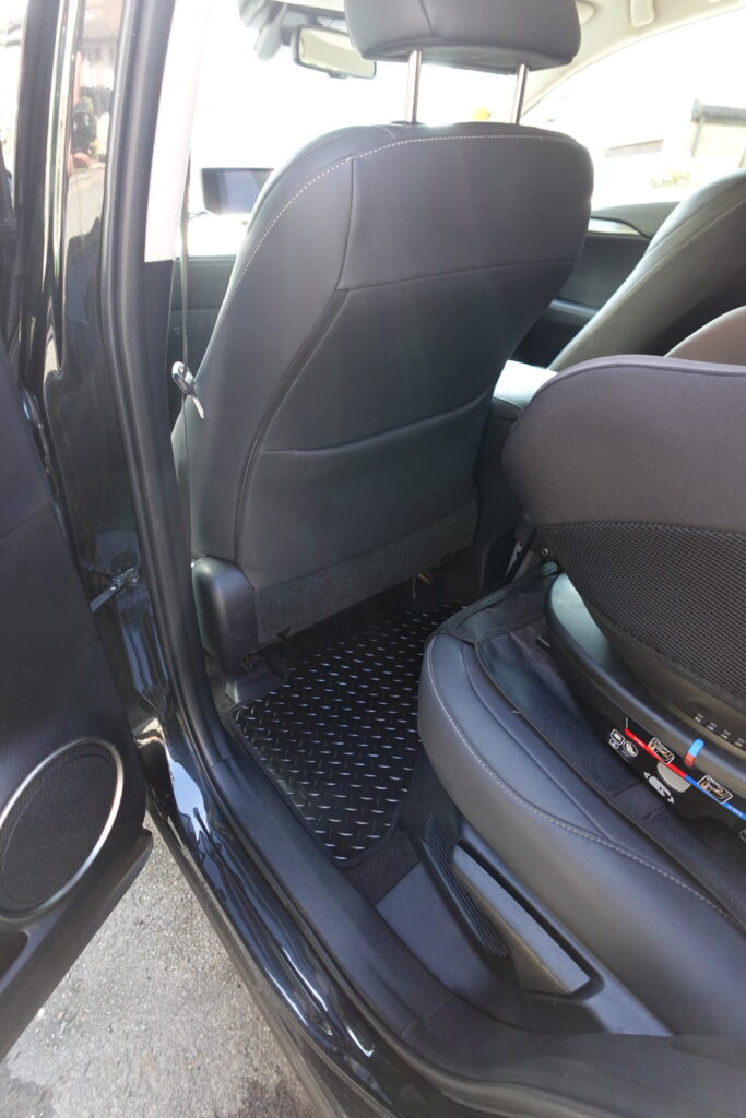 Clean black car interior showcasing detailed floor mats and seat rails after a full detail.