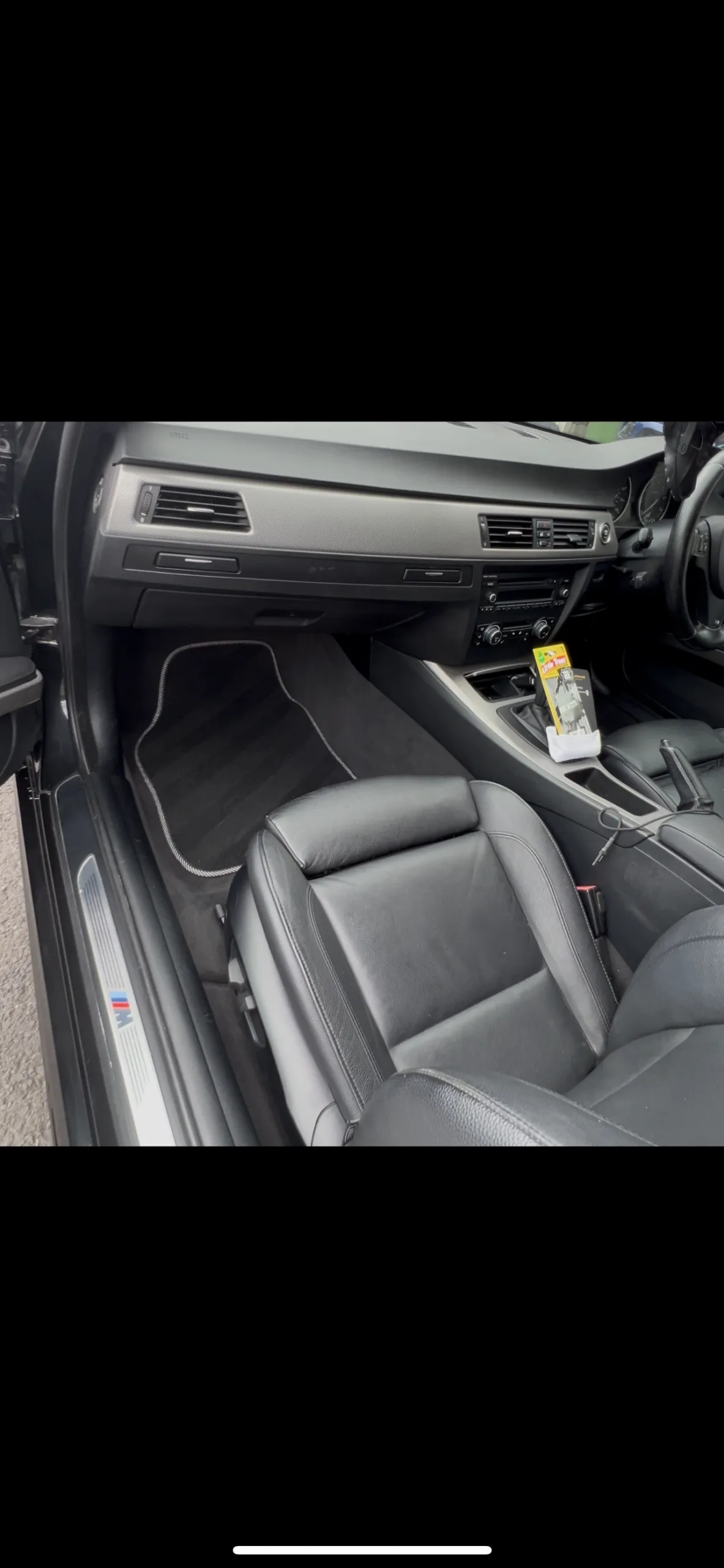Clean BMW interior showing detailed passenger leather seat and footwell with carpet lines by Elite AutoCare.